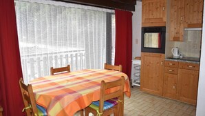 A room with a dining table, chairs, a kitchen area, and a window with curtains. - 1st floor, balcony, tv, 44m², Pralognan-la-Vanoise (Pralognan-la-Vanoise)
