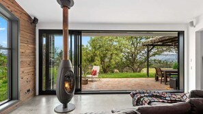 A modern living room with a large glass door leading to an outdoor patio. - Moosewood House, Kangaroo Valley (Kangaroo Valley)