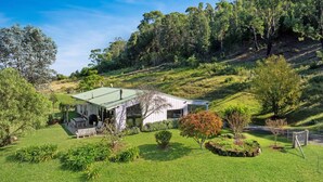 Ein modernes Haus mit Gründach, umgeben von üppiger Vegetation und Hügeln.