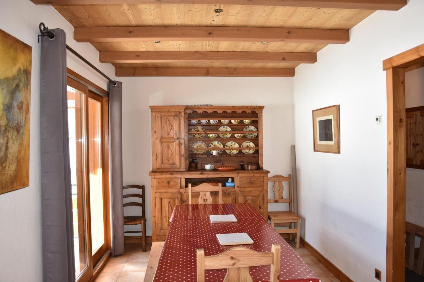 Un coin repas avec une table et des chaises en bois, un buffet contenant de la vaisselle et un plafond en bois.