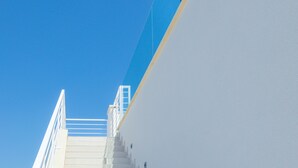 A staircase leading up to a white building with a blue sky in the background.