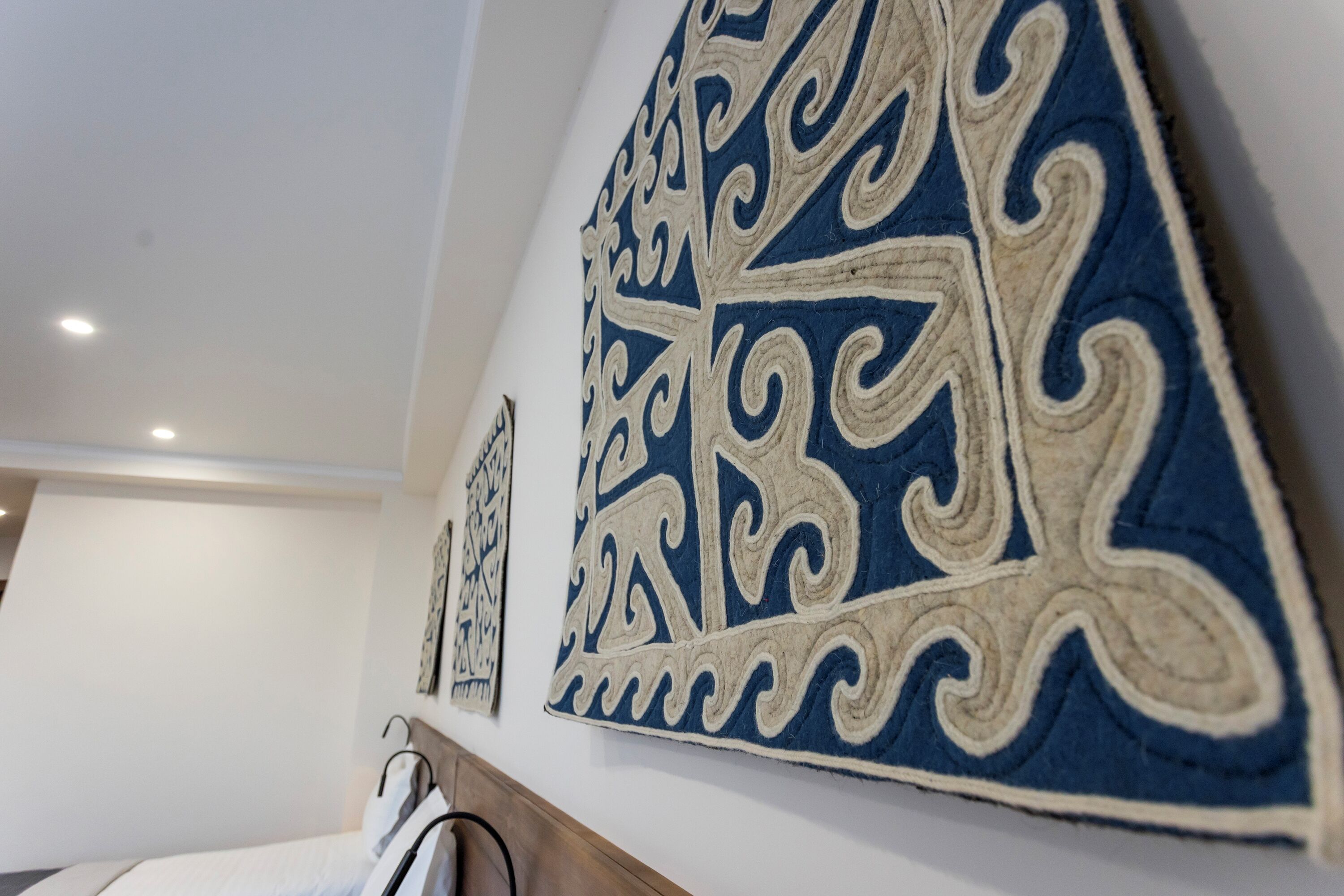 Une chambre avec un lit, un mur orné de motifs décoratifs et une tête de lit en bois.