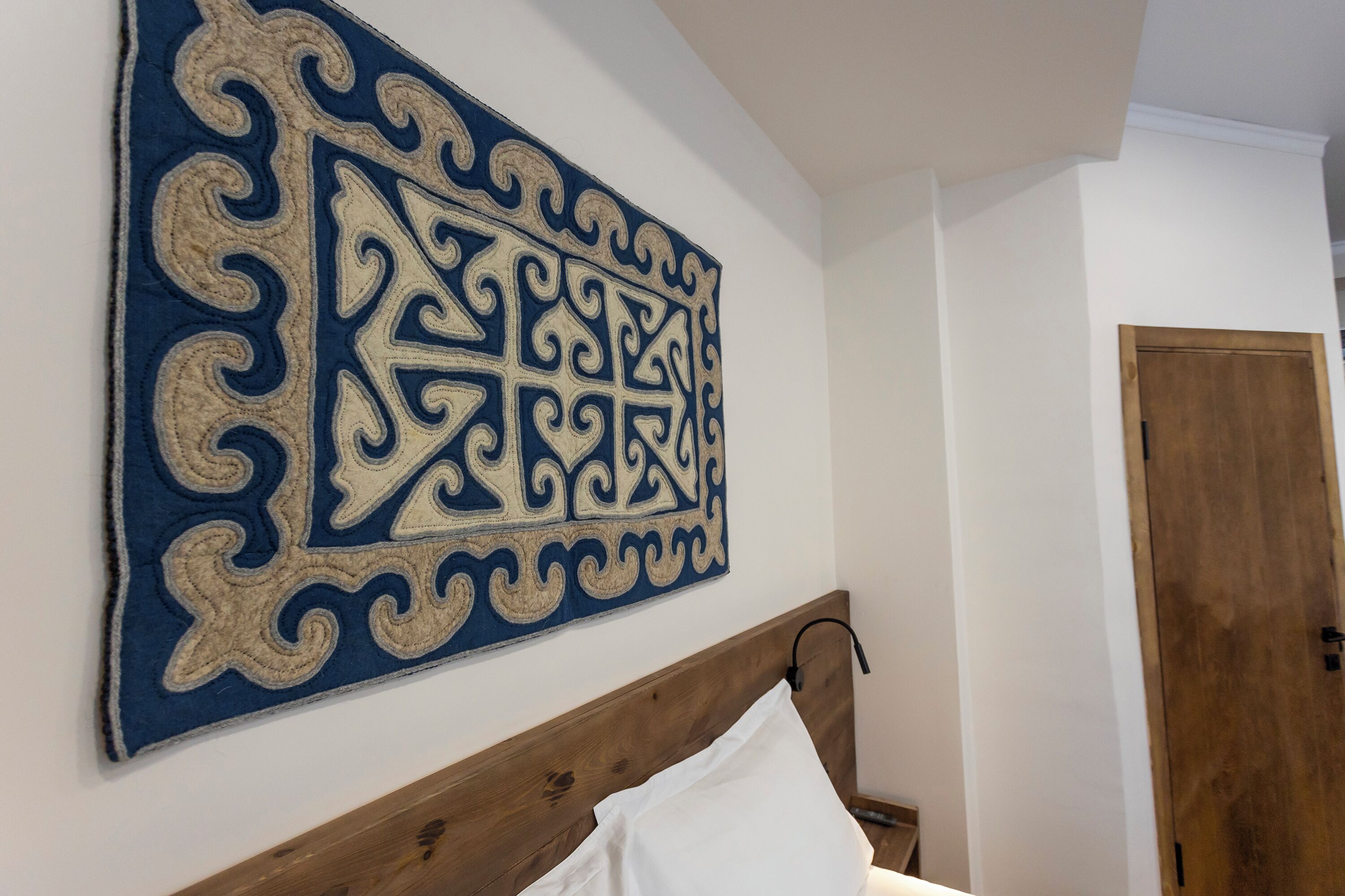 Une chambre à coucher avec une tête de lit en bois, un oreiller blanc et une décoration murale à motifs géométriques.