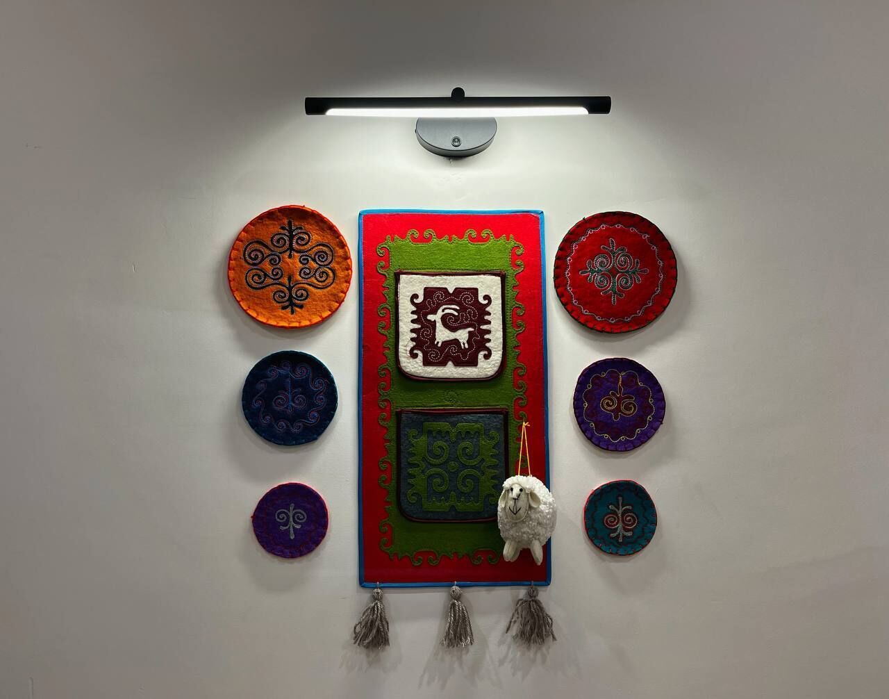 A wall with a central decorative panel featuring a sheep and geometric patterns, surrounded by circular designs with animal motifs.