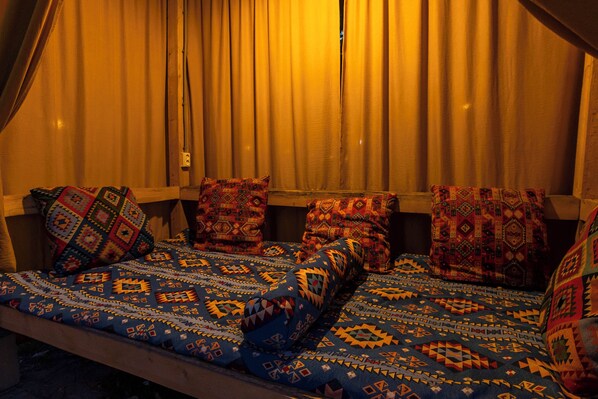 A room with a bed covered in patterned bedding, a window with curtains, and a wall-mounted light fixture. - Akjola (Bishkek)
