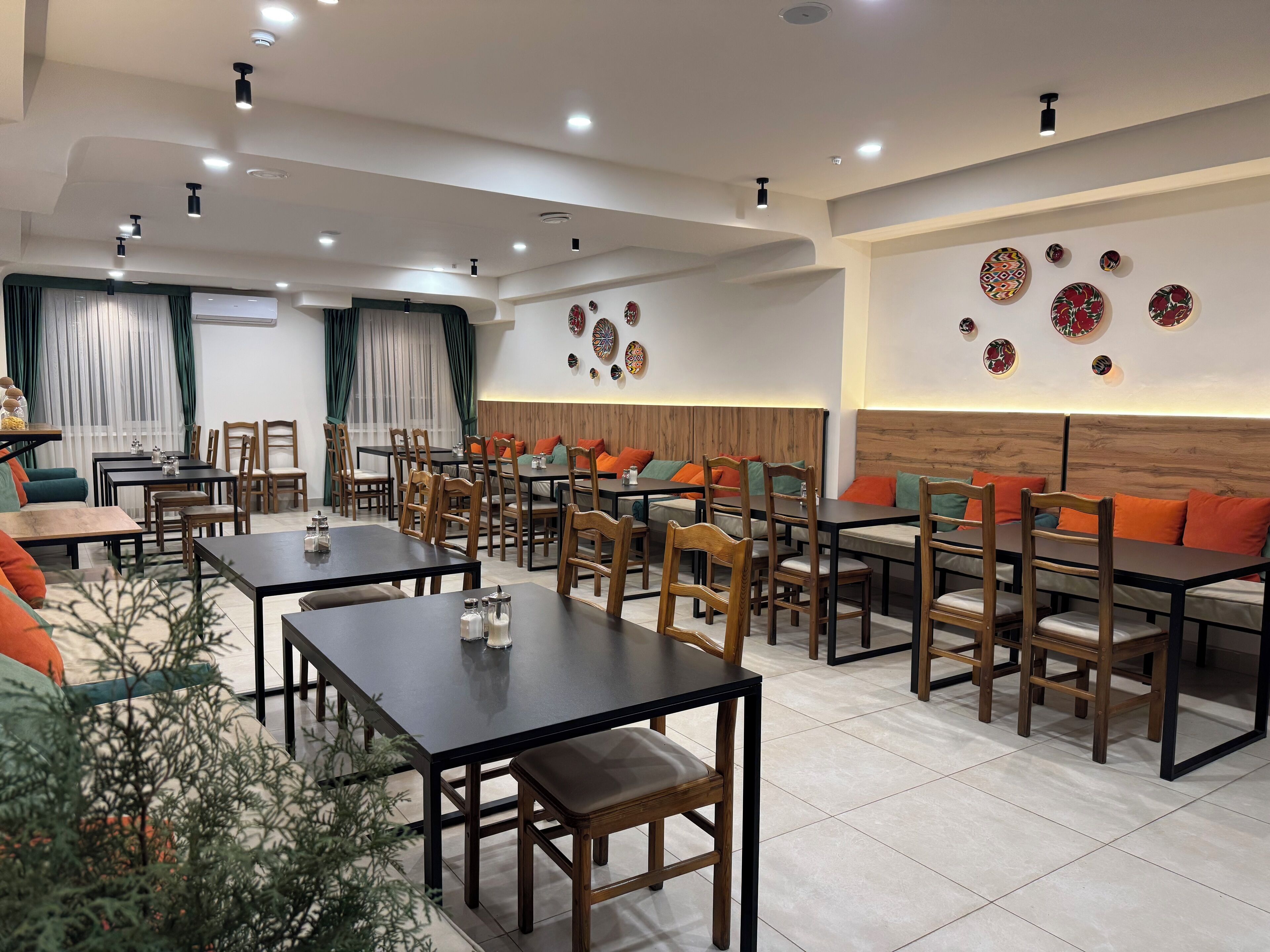 A modern dining area with multiple tables and chairs, a wooden accent wall, and decorative wall art.