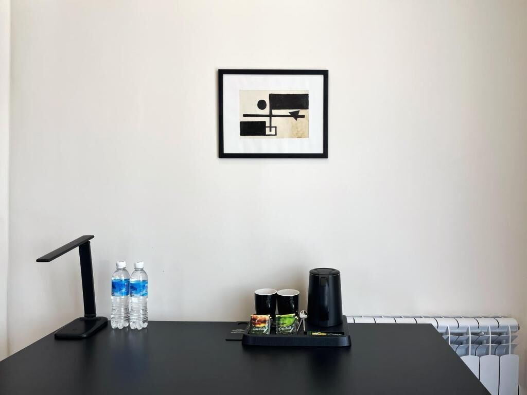 A black desk with a coffee maker, two water bottles, and two cups.