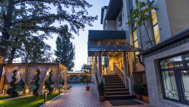 A well-lit outdoor area with a paved walkway, a covered entrance, and a staircase leading to a building. - Akjola (Bishkek)
