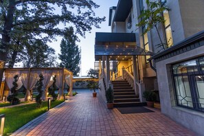 A well-lit outdoor area with a paved walkway, a covered entrance, and a staircase leading to a building. - Akjola (Bishkek)