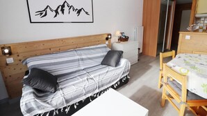 A cozy room with a striped sofa, a small table, and a wooden cabinet. - 50m from ski slopes, 4th floor, balcony, tv, 34m², Tignes (Tignes)