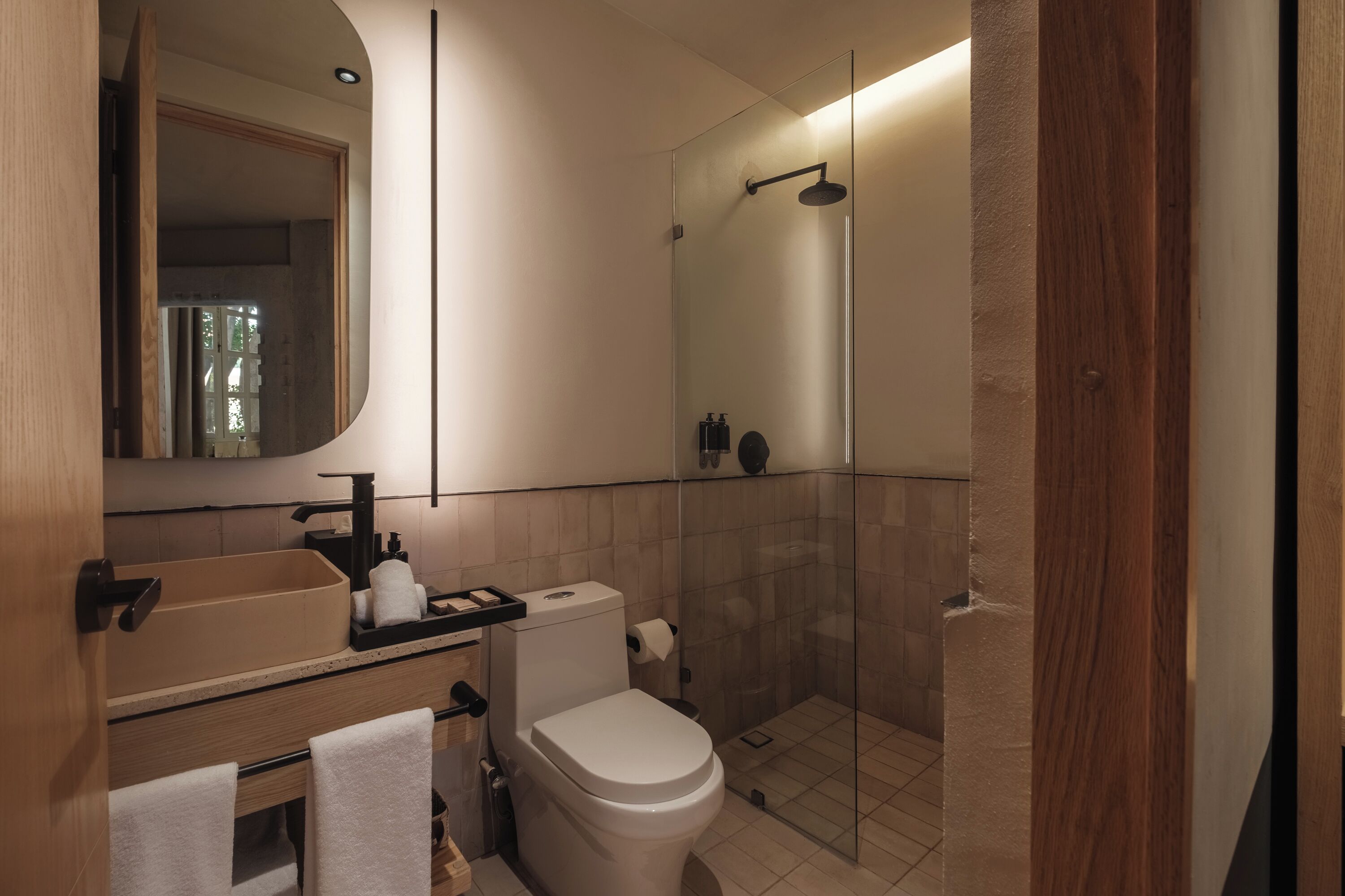Une salle de bain moderne avec une douche à parois de verre, des toilettes, un lavabo avec un miroir et un porte-serviettes.