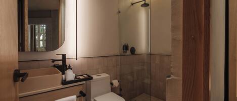 Une salle de bain moderne avec une douche à parois de verre, des toilettes, un lavabo avec un miroir et un porte-serviettes.