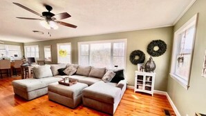 A spacious living room with a sectional sofa, a ceiling fan, and a fireplace.