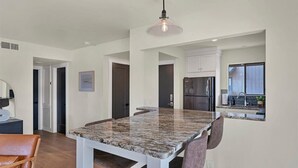 A modern kitchen with white cabinets, a granite countertop, and a hanging light fixture. - Pick of the Pines Pinehurst (Pinehurst)