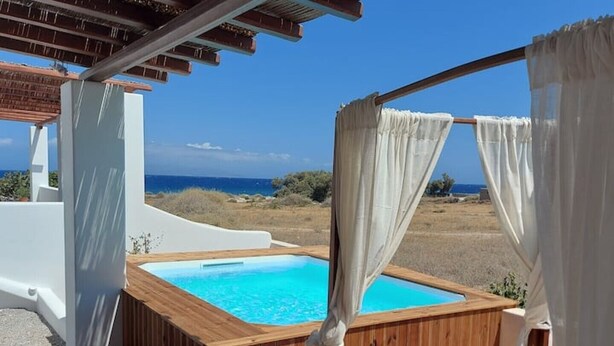 A wooden hot tub with white curtains, a wooden deck, and a view of the sea. - Villa Ersa @home by the sea (Santorini)