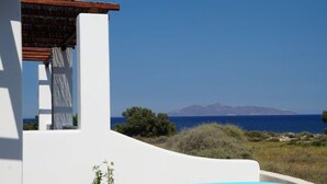 A white building with a pool, overlooking a clear blue sea and distant mountains. - Villa Ersa @home by the sea (Santorini)