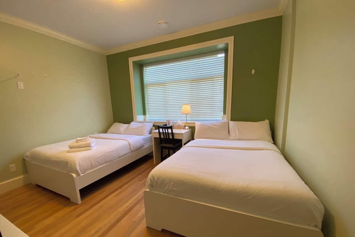 A room with two single beds, a desk, and a chair.