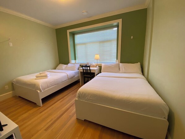 A room with two single beds, a desk, and a chair. - Victory House (Burnaby)