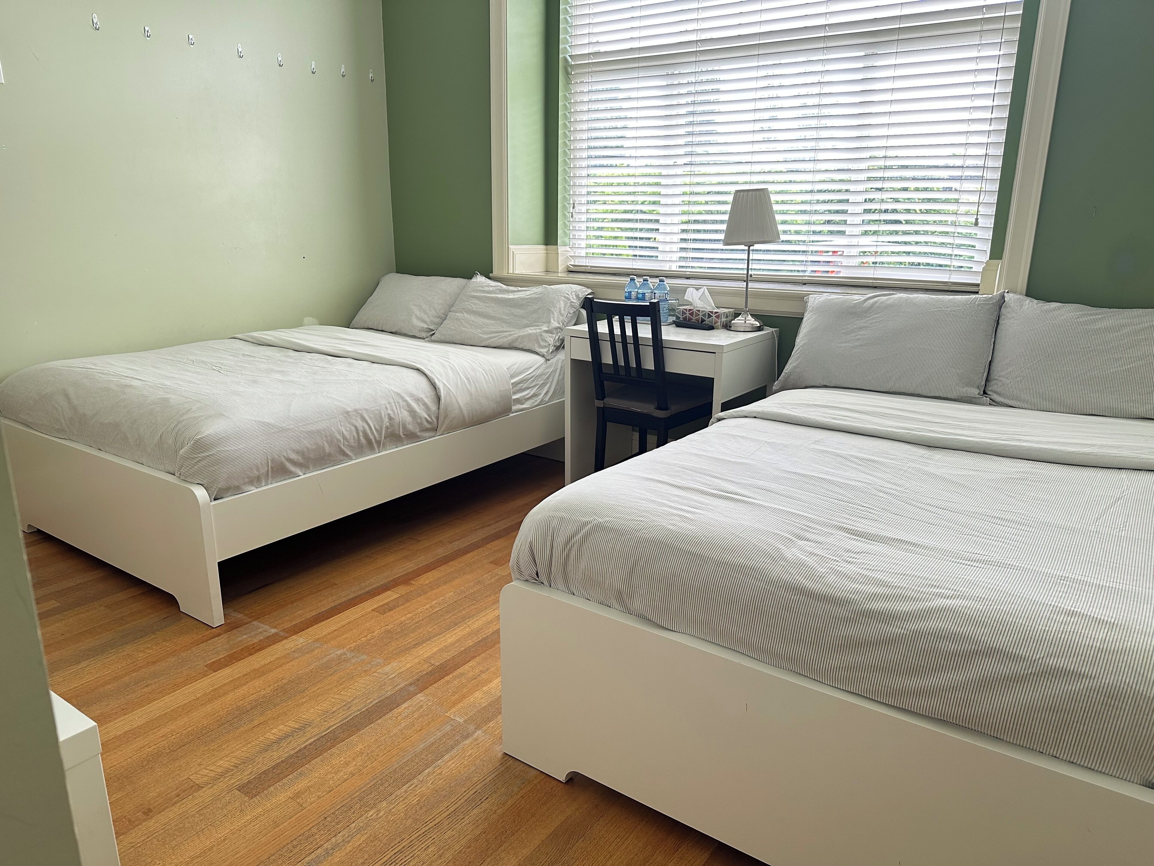 A bedroom with two beds, a desk, and a chair.