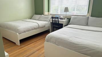 A bedroom with two beds, a desk, and a chair.