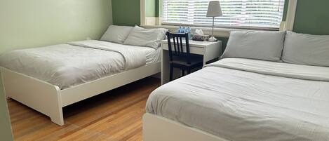A bedroom with two beds, a desk, and a chair.