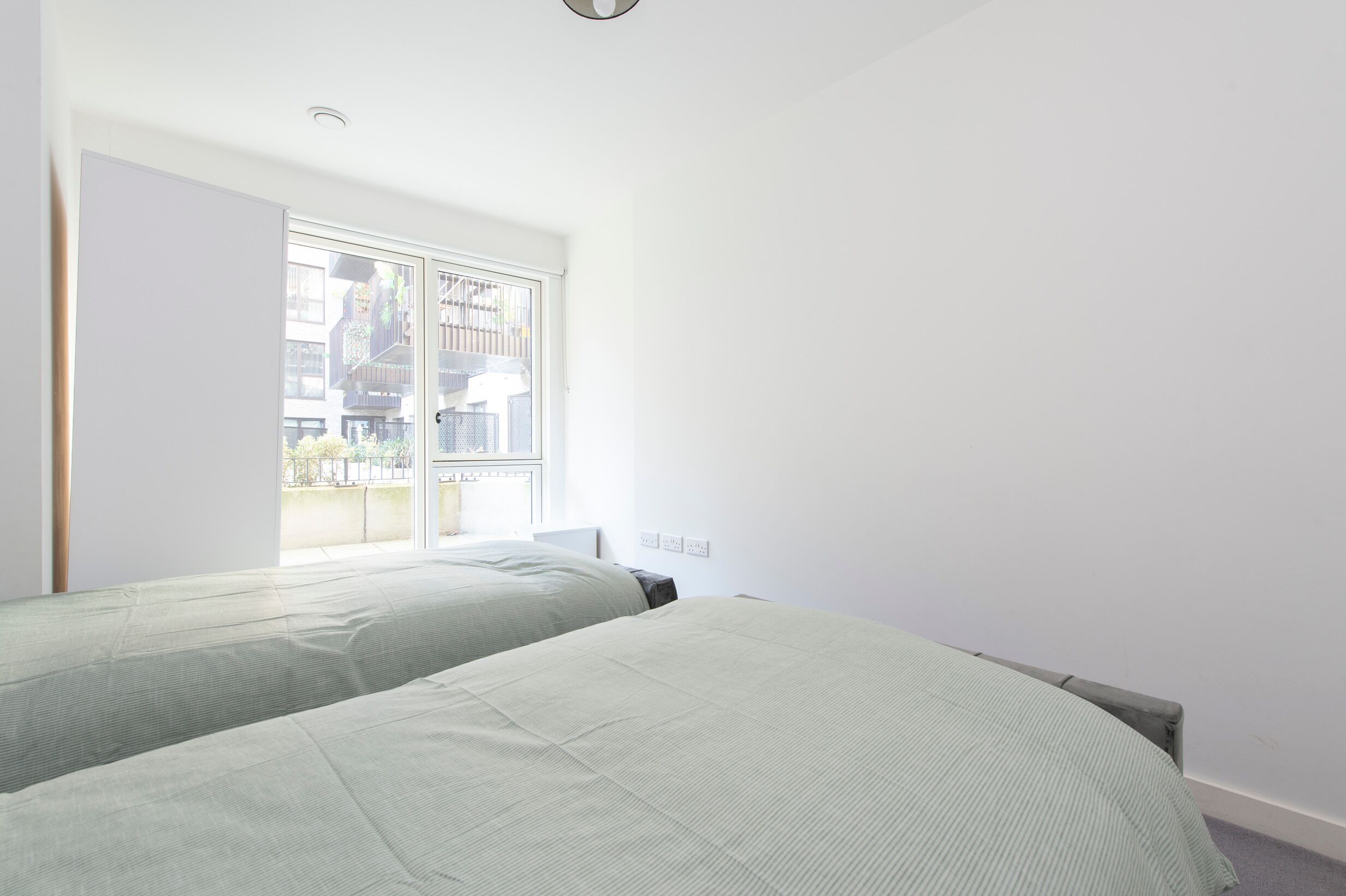 A bedroom with two beds, a window, and a door.