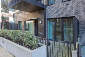 Un bâtiment moderne avec une façade en briques, de grandes fenêtres et une clôture en métal.