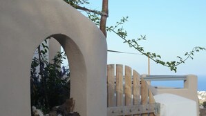 A white building with a wooden gate and an arched window. - House with sea view 'Avgi' @seaside house (Santorini)