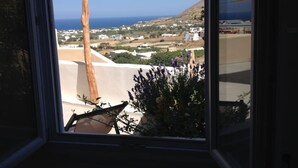 A view from a window overlooking a coastal landscape with buildings and a clear sky. - House with sea view 'Avgi' @seaside house (Santorini)