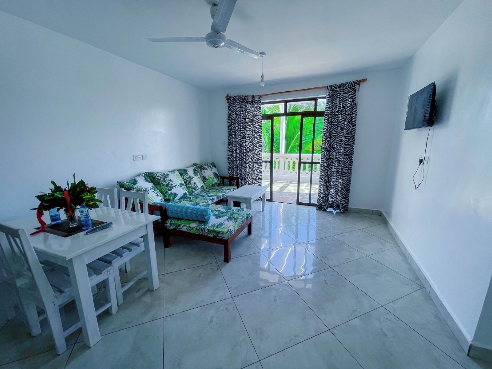 Una habitación amplia con sofá, mesa de comedor y ventilador de techo.