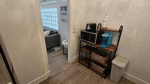Un couloir avec un four à micro-ondes posé sur une étagère, une poubelle et une fenêtre donnant sur une plage.