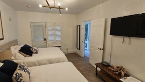 Une chambre d’hôtel avec deux lits, une télévision, une lampe et une porte donnant sur un balcon.