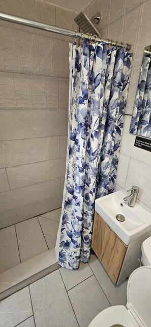 A bathroom with a shower curtain, a sink, and a toilet. - Sirena Azul SoBe Suite 2 (Miami Beach)