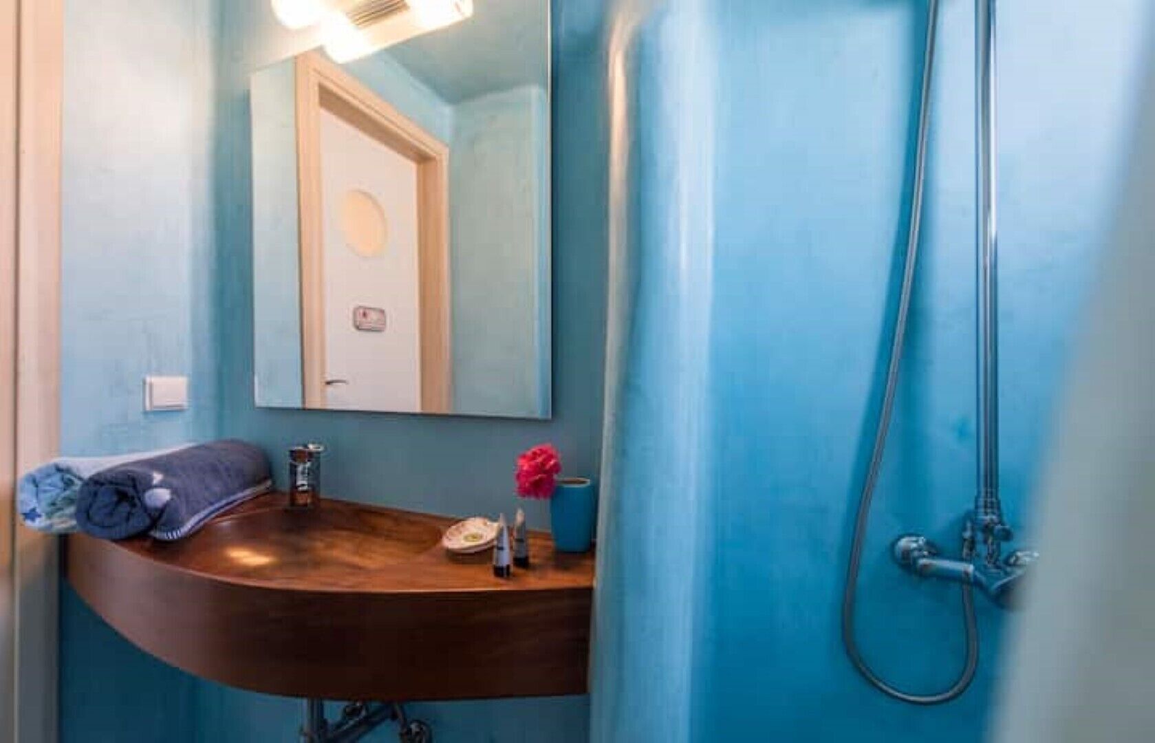 A bathroom with a wooden vanity, a mirror, a towel, and a shower.