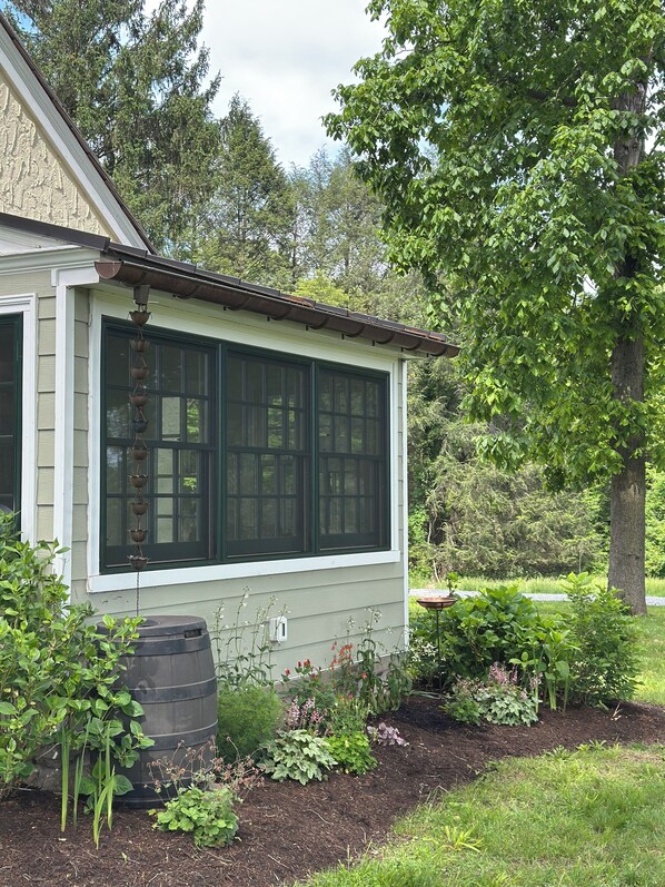 A house with a large window, a small garden with various plants, and a barrel. - Country School House at Solidago Farm
Unique, cozy small farm experience! (West Chester)