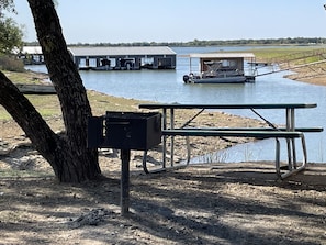 A picnic table and a trash bin near a body of water with a boat dock and buildings in the background. - Village Inn (Breckenridge)