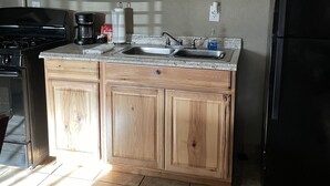 A kitchen with wooden cabinets, a stainless steel sink, a black refrigerator, and a coffee maker.
