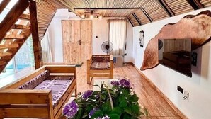 A cozy room with a wooden ceiling, a fireplace, a bed, a chair, and a large window. - Lekki Beach Resort- 1 bed & private pool (Lekki)