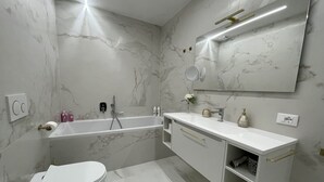 A modern bathroom with a bathtub, toilet, and vanity with a mirror.