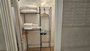A metal wire shelf unit with folded towels and a striped cloth in a hallway. - Sirena Azul SoBe Suite 3 (Miami Beach)