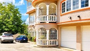A multi-story building with balconies, a garage, and parked cars.