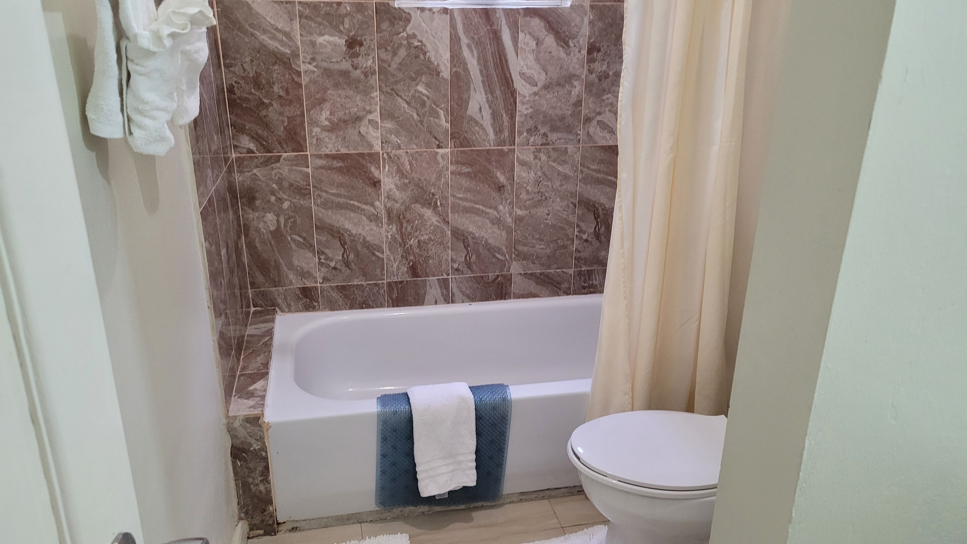 A bathroom with a bathtub, a toilet, and a shower curtain.