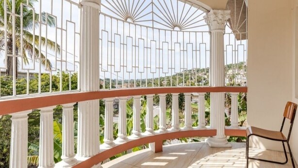 Ein Balkon mit weißen Säulen und Blick auf viel Grün.