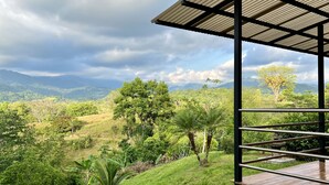Terraço com vista para colinas e montanhas verdejantes sob um céu nublado.