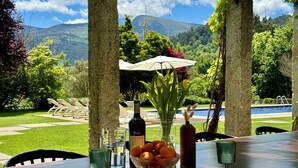 A dining table set outdoors with a view of mountains and a pool. - Quinta Trindade (Arouca)
