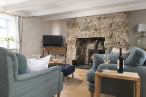 A cozy living room with a stone fireplace, a television, and seating.