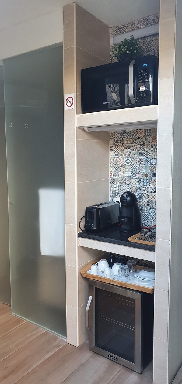 A kitchenette with a microwave, toaster, coffee maker, and a mini-fridge. - Isabel Guest House (Almada)