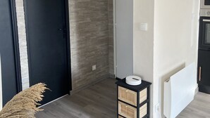 Una cocina moderna con horno integrado, una pequeña mesita negra con un objeto blanco encima y una puerta con un letrero en la parte superior.