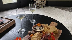 Ein Esstisch mit einer Wurstplatte, zwei Gläsern Weißwein und einem Kamin im Hintergrund.