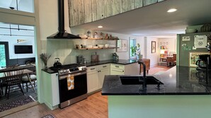 Eine moderne Küche mit Holzausstattung, einer zentralen Kochinsel und einem Essbereich mit Teppich.